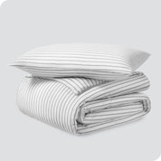 A folded stack of a printed flannel duvet cover with one pillow on top.