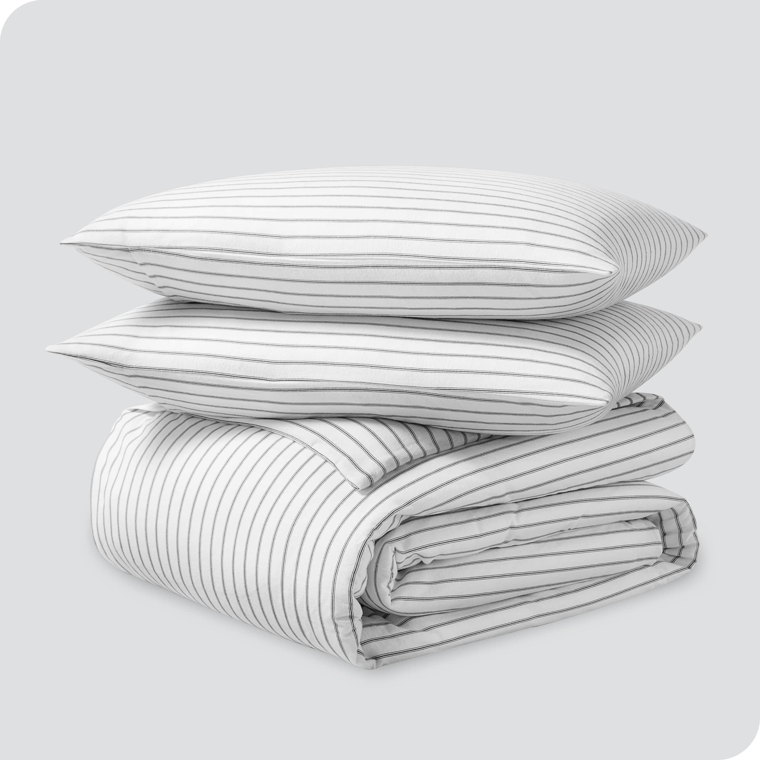A folded stack of a printed flannel duvet cover with two pillows on top.